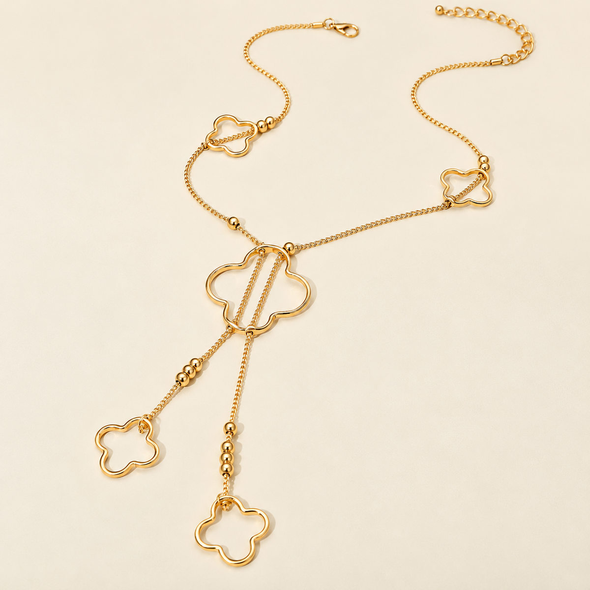 Gold clover charm lariat necklace with dangling chains and open clover pendants